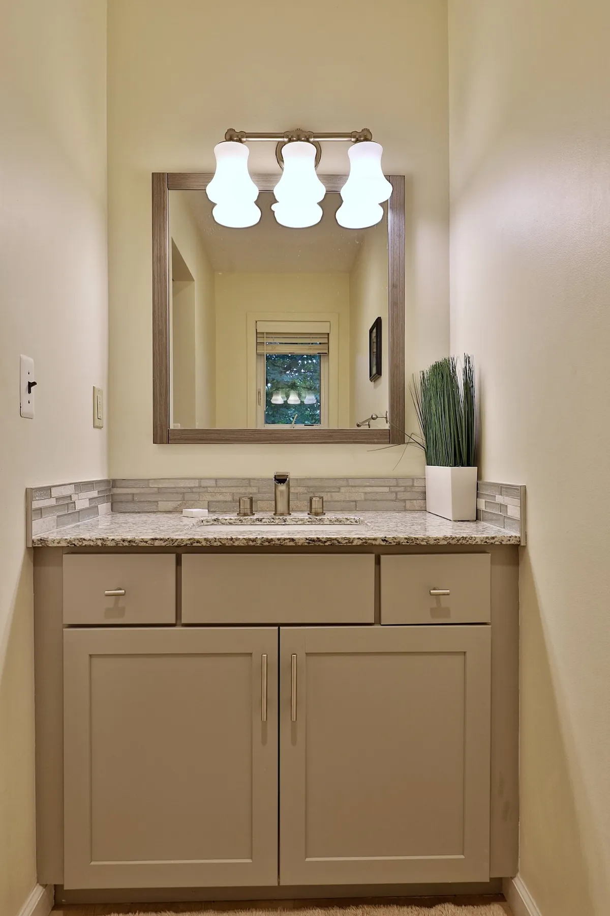 A bright and modern bathroom with a sleek sink, a large mirror, contemporary lighting, and a decorative plant on the countertop. The overall feel is clean and inviting, ideal for morning routines or refreshing after a day outdoors.