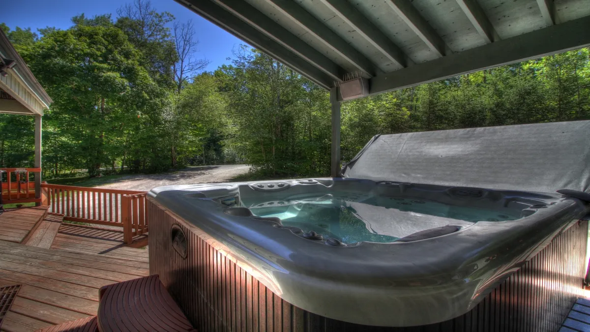 A tranquil hot tub sits on the deck, surrounded by greenery and open sky. It invites relaxation and socializing, with a sense of privacy and immersion in nature, especially appealing for starlit soaks after adventurous days.