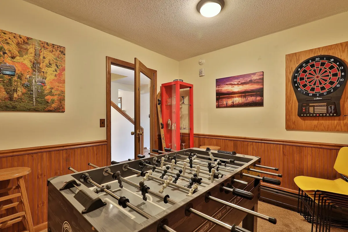An interior view of a game room featuring a foosball table, dartboard, and colorful artwork. The space is designed for fun and socializing, ideal for group entertainment after outdoor adventures.